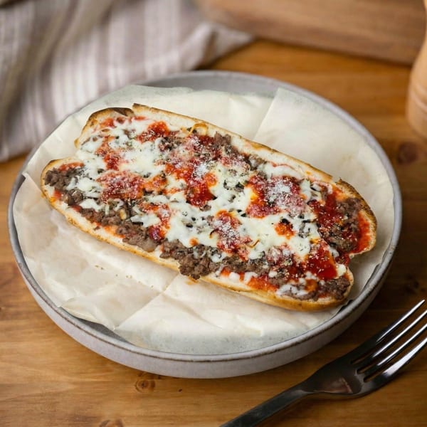A savory meatball sub with melted mozzarella, marinara sauce, and parmesan cheese on a plate.