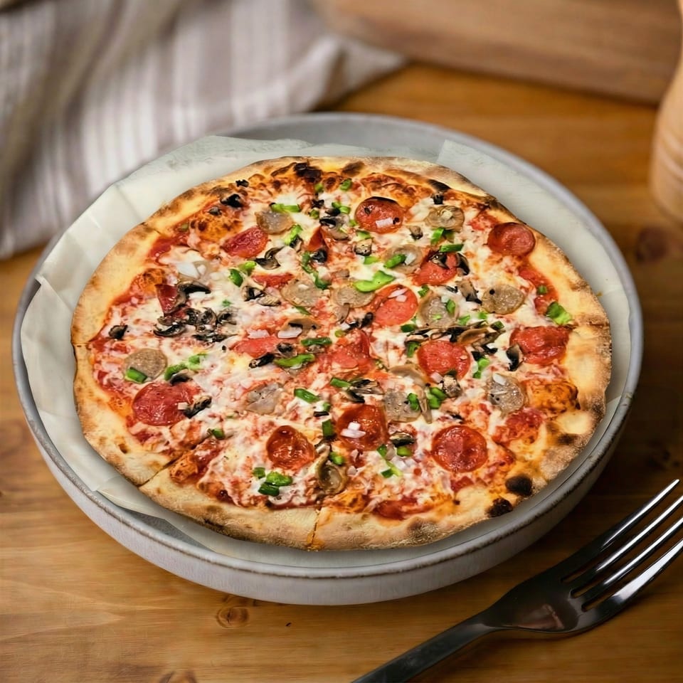 A whole pizza with pepperoni, sausage, mushrooms, and green peppers on a wooden table.